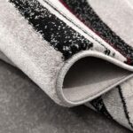 Close-up of folded striped carpet on floor.
