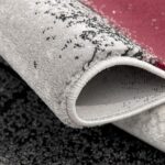 Close-up of rolled textured carpet with red accent.