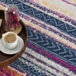Colorful patterned rug with coffee and book on tray.