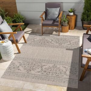 Outdoor patio with patterned rug and seating area.