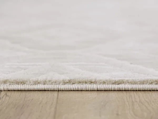 Close-up of white rug on wood floor.