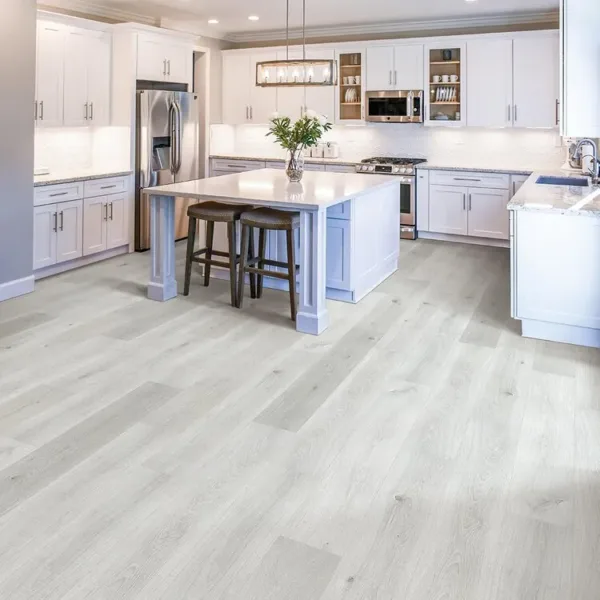 Modern white kitchen with island and light wood flooring.