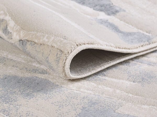 Close-up of folded beige gray area rug