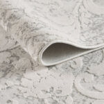 Close-up of rolled ornate beige carpet texture.