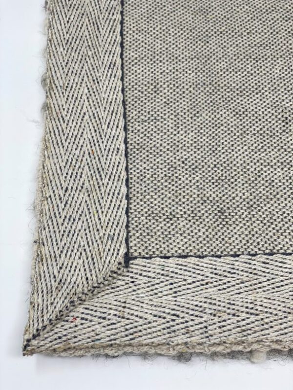 Close-up of woven herringbone rug corner.