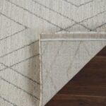 Geometric rug on wooden floor corner reveal.