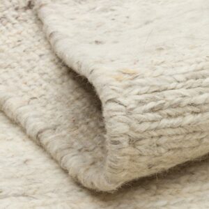 Close-up of folded cream wool rug texture