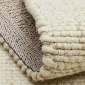 Close-up of folded cream woven wool rug