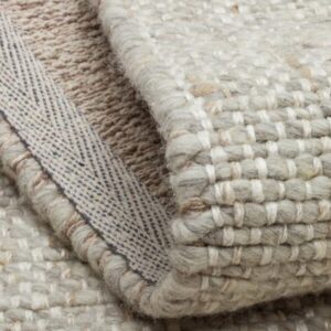 Close-up of folded woven beige rug with fabric backing
